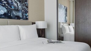 A hotel room with a bed, a nightstand, a lamp, and a large mirror.