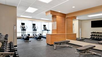 A gym with exercise equipment, a reception desk, and a mirror.