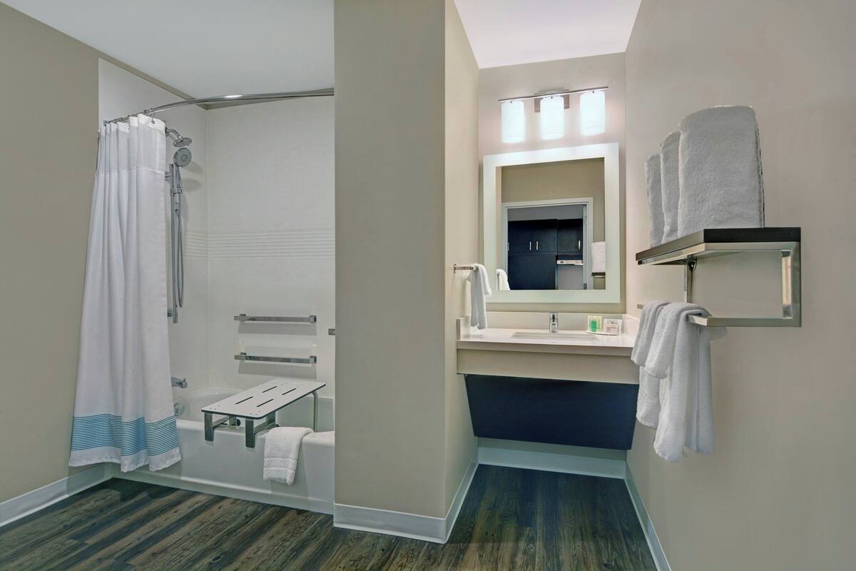 A modern bathroom with a shower, a sink, a mirror, and a towel rack.