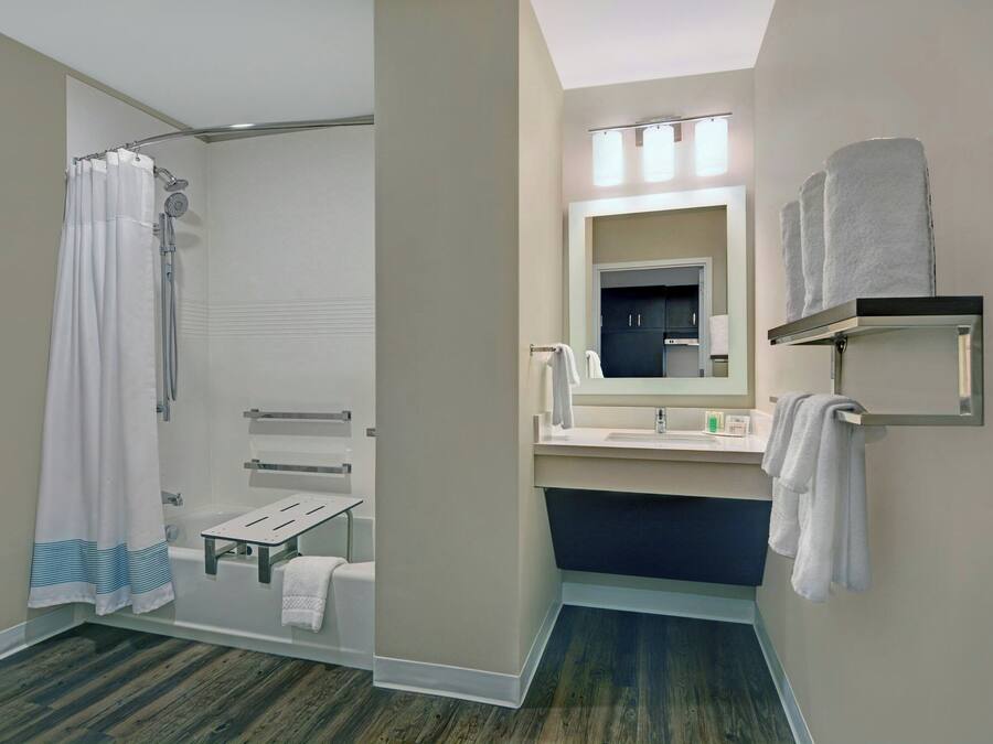 Un baño moderno con ducha, lavamanos, espejo y perchero para toallas.