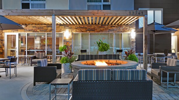 An outdoor seating area with a fire pit, wicker furniture, and a covered patio. - TownePlace Suites by Marriott Jacksonville East (Jacksonville)