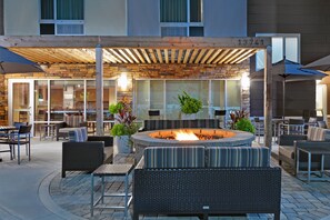 Un área de estar al aire libre con una chimenea, muebles de mimbre y un porche cubierto.