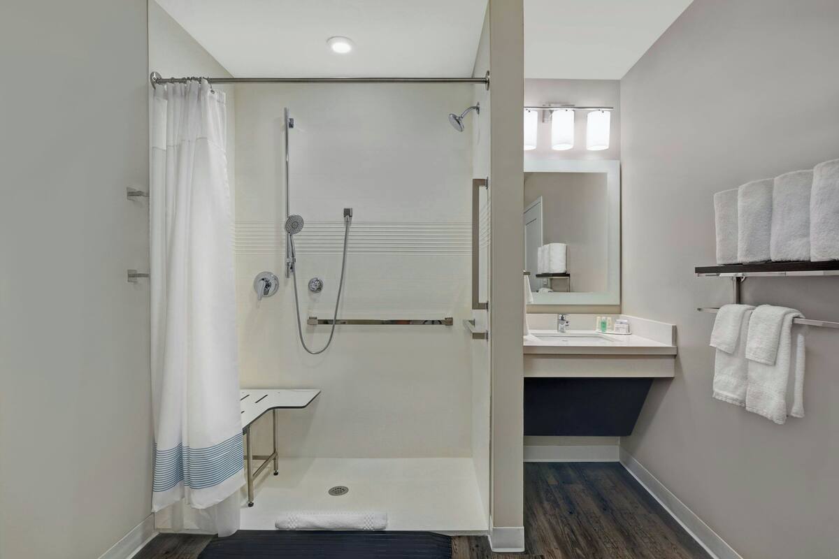 A modern bathroom with a glass-enclosed shower, a white sink, and a towel rack.