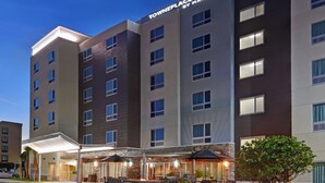 A multi-story hotel with a modern design, featuring a covered outdoor area with seating and a fire pit. - TownePlace Suites by Marriott Jacksonville East (Jacksonville)
