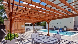 An outdoor patio with a pool, wooden pergola, and seating area. - TownePlace Suites by Marriott Jacksonville East (Jacksonville)
