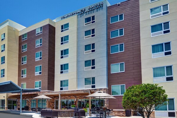 Un hotel de varios pisos con diseño moderno, que presenta una combinación de fachadas marrones y beiges, grandes ventanales y zonas de estar al aire libre con sombrillas.