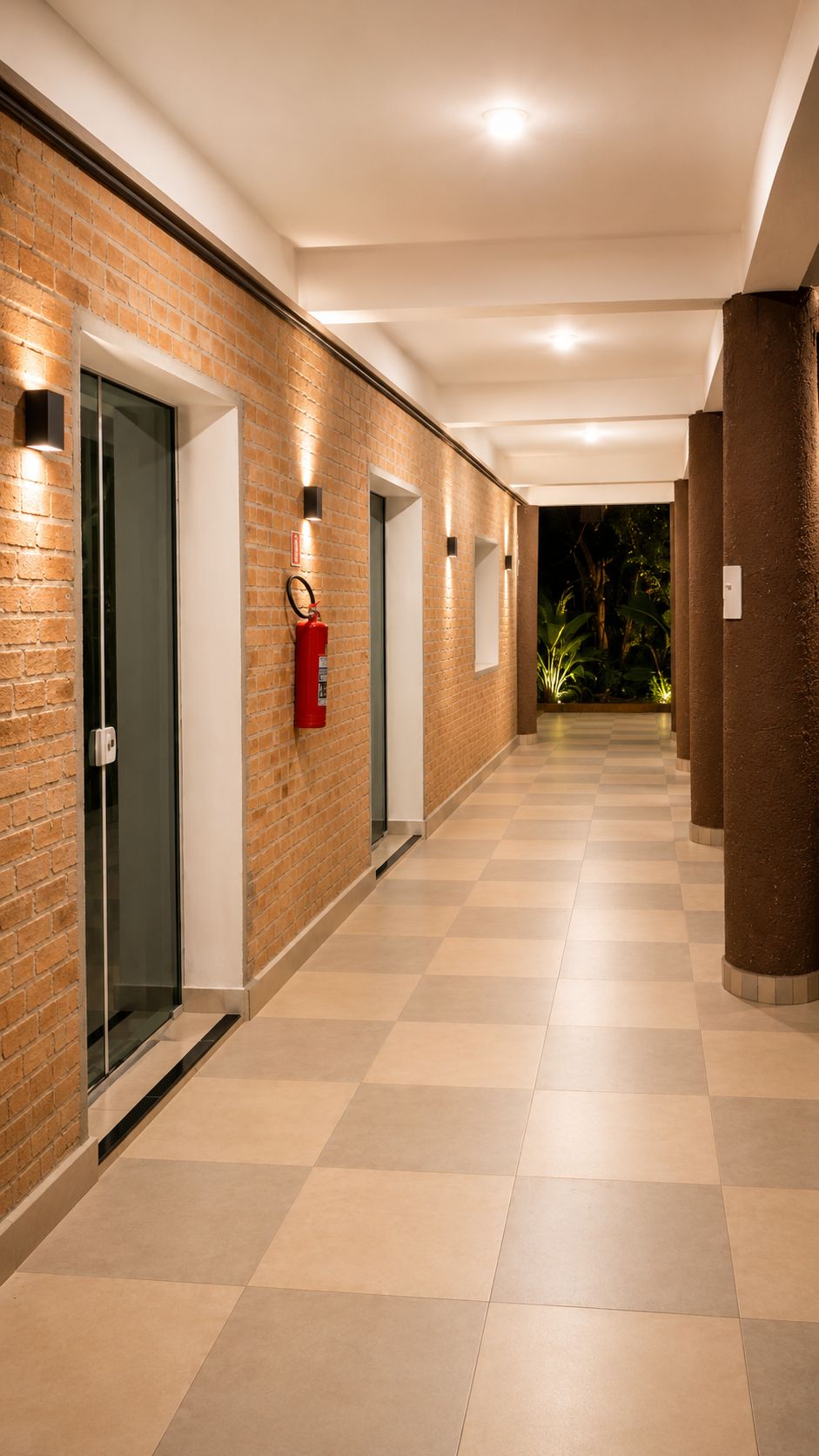 A corridor with a checkered floor, brick walls, and recessed lighting.