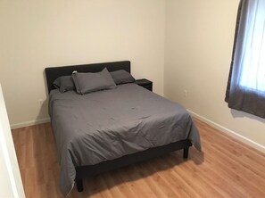 Cozy retreat with a single bed, dark headboard, and grey bedding, set against a simple, clean backdrop.