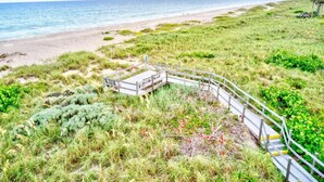 A coastal path with a wooden bridge leading to a beach.