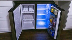 Een compacte koelkast met twee plateaus, waarvan één met drankjes en de andere met etenswaren.