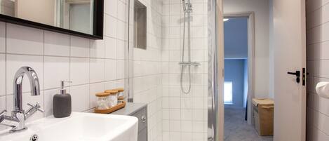 A modern bathroom with a white sink, mirror, and shower.