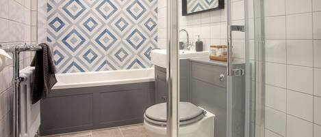 Een moderne badkamer met douche, toilet en bad.