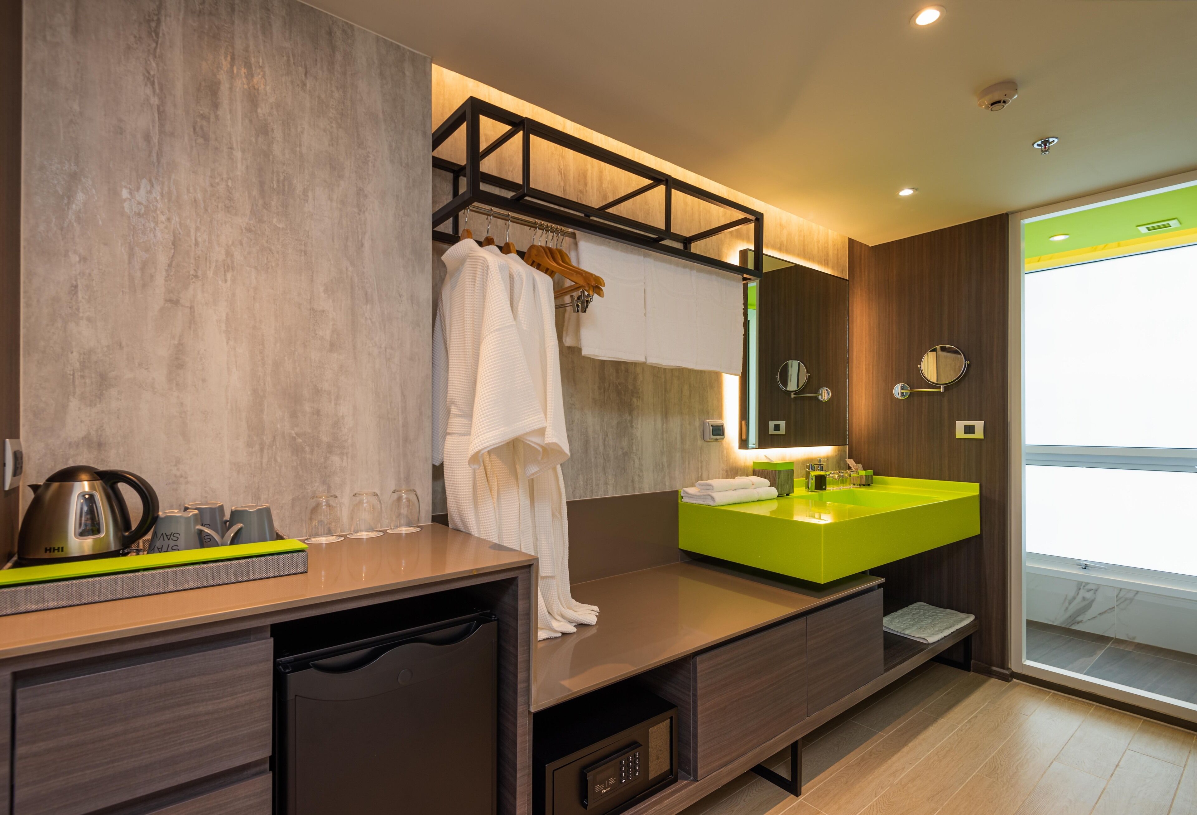 A modern bathroom with a wooden vanity, a green sink, and a large mirror.