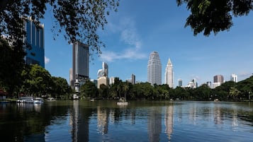 A cityscape with modern buildings, a calm lake, and lush greenery.