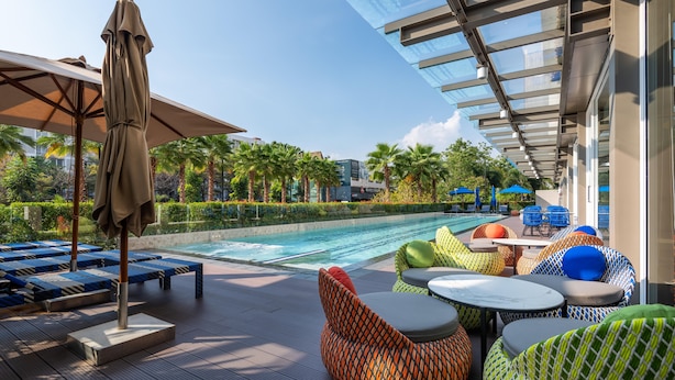 A poolside area with lounge chairs, umbrellas, and a glass-enclosed walkway.