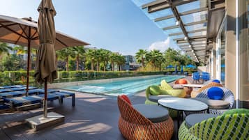 Una piscina al aire libre, sombrillas, sillones reclinables de piscina