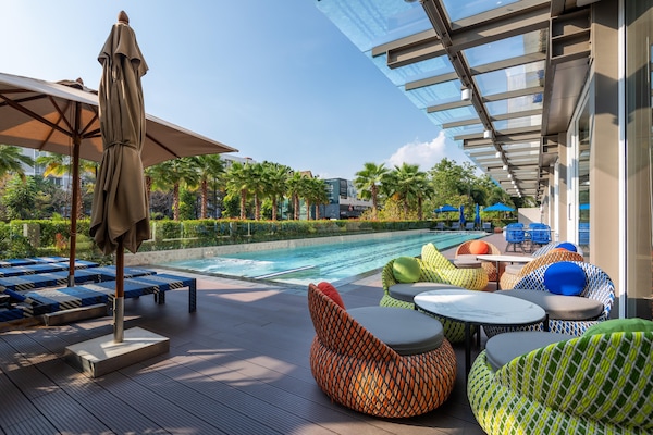 Una piscina al aire libre, sombrillas, sillones reclinables de piscina