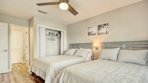 A bedroom with two beds, a ceiling fan, and a closet with open doors.