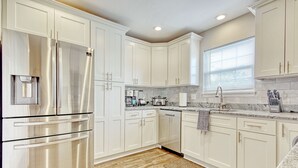 A modern kitchen with white cabinets, stainless steel appliances, and a granite countertop.