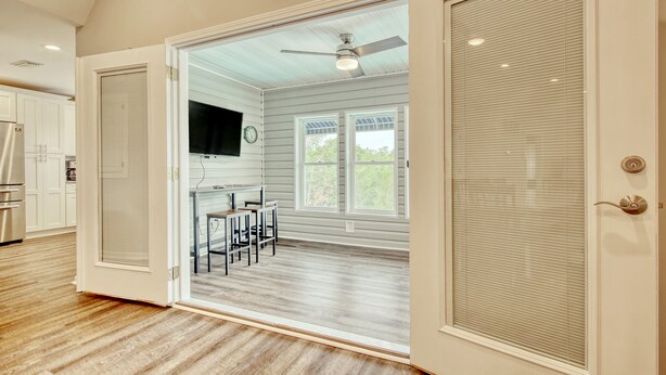 A spacious kitchen with white cabinets, a stainless steel refrigerator, and a dining area with a table and chairs.