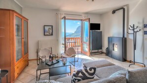 A living room with a sofa, a table with a tray, a chair, a cabinet, a fireplace, and a balcony with a view. - Balcone sul Lago - Apartment with Amazing View Terrace, Tremosine, Italy (Tremosine)
