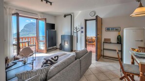 A living room with a sofa, a dining table, a TV, and a view of the outdoors. - Balcone sul Lago - Apartment with Amazing View Terrace, Tremosine, Italy (Tremosine)