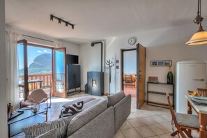 Una sala de estar con sofá, una mesa de comedor, televisor y vistas al exterior.