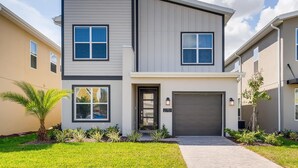 A modern two-story house with a garage, a well-maintained lawn, and a clear sky. - Luxury 5BR Family Oasis with Private Pool - 13 Guests (Kissimmee)