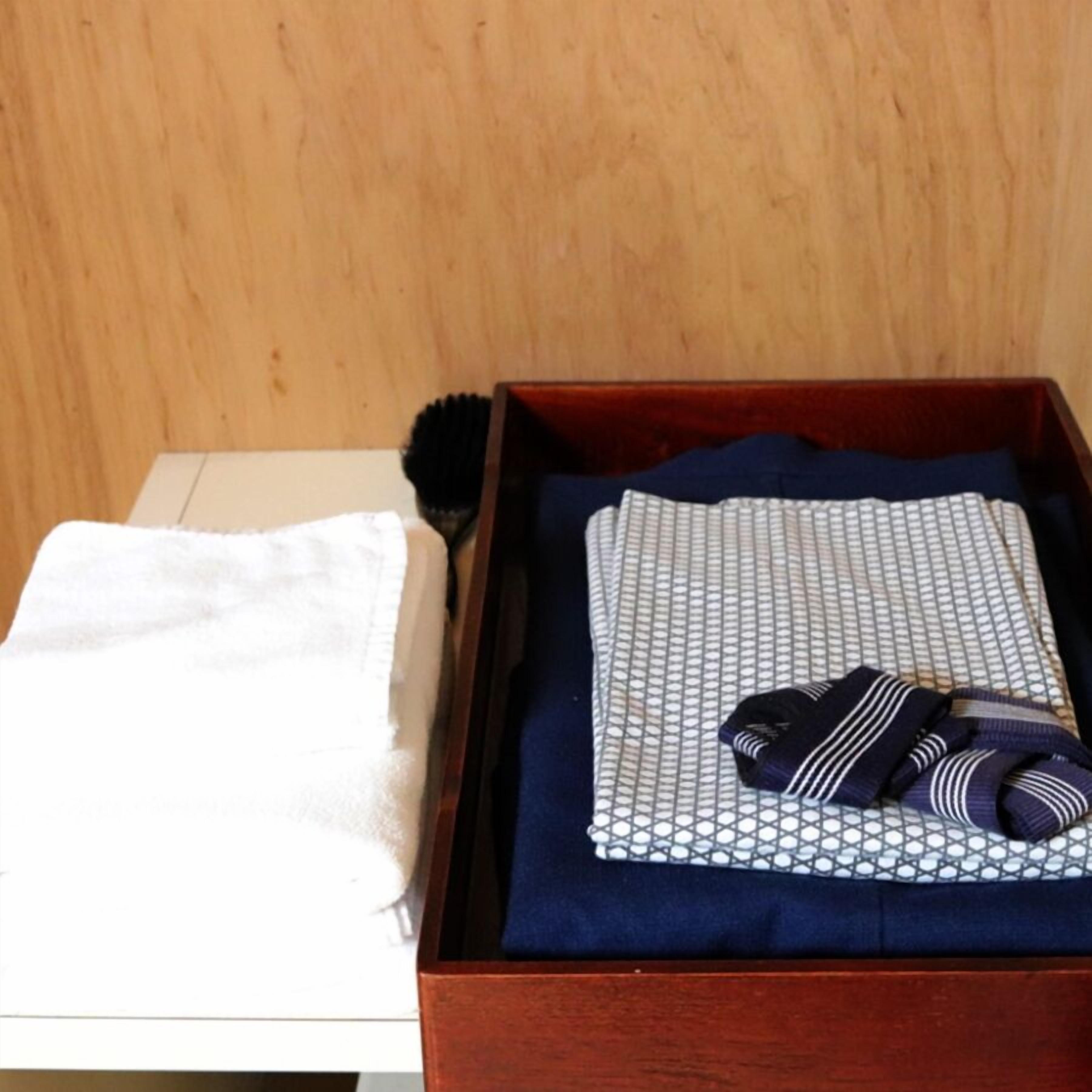 A wooden chest with a folded white towel and a patterned pillow inside.