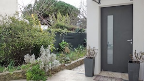 Un bâtiment moderne avec une porte sombre, un mur en pierre et une variété de plantes.