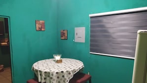 Un'area ristoro con un tavolo rotondo ricoperto da una tovaglia a pois, due sgabelli rossi e un piccolo vaso con fiori.
