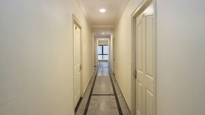 A narrow hallway with white walls, a tiled floor, and doors on both sides leading to rooms. - OYO 10321 Koramangala (Bengaluru)