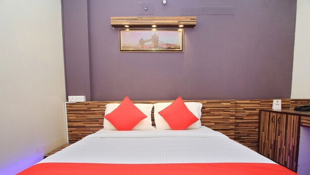 A bed with a white and red bedspread, two red pillows, and a wooden headboard. - OYO 10321 Koramangala (Bengaluru)