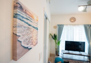 Ein Wohnzimmer mit einem großen Meeresbild, einem Fernseher und einer Zimmerpflanze.