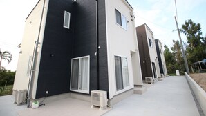 Un edificio moderno de dos pisos con techo plano, ventanas amplias y una unidad de aire acondicionado visible.