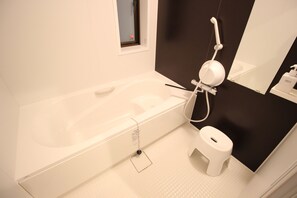 Ein modernes Badezimmer mit Badewanne, Toilette und einem kleinen Fenster.