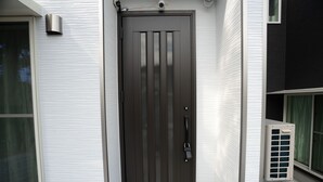 Una puerta marrón oscuro con rendijas verticales, un pomo y una cerradura.