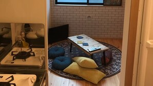Un espace de vie compact comprenant une petite table à manger, un canapé et une grande fenêtre.
