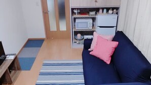 Un espacio habitable compacto con sofá, microondas y una pequeña kitchenette.
