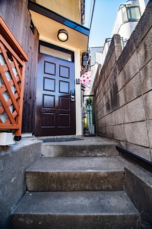 A narrow stairway leading to a dark brown door with a small circular window above it.