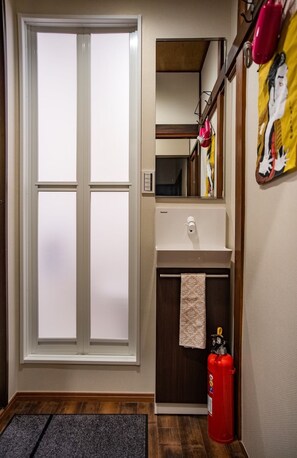 A hotel room with a large window, a sink, a towel, a fire extinguisher, and a mirror.