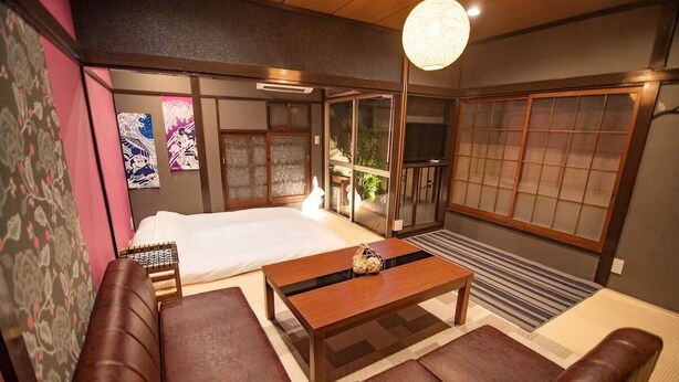 A traditional Japanese-style room with tatami flooring, a low wooden bed, a wooden coffee table, and a sliding door. - A0 Shinjuku Big House (Tokyo)