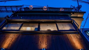 A building with a wooden facade, large windows, and a balcony with circular decorations. - A0 Shinjuku Big House (Tokyo)