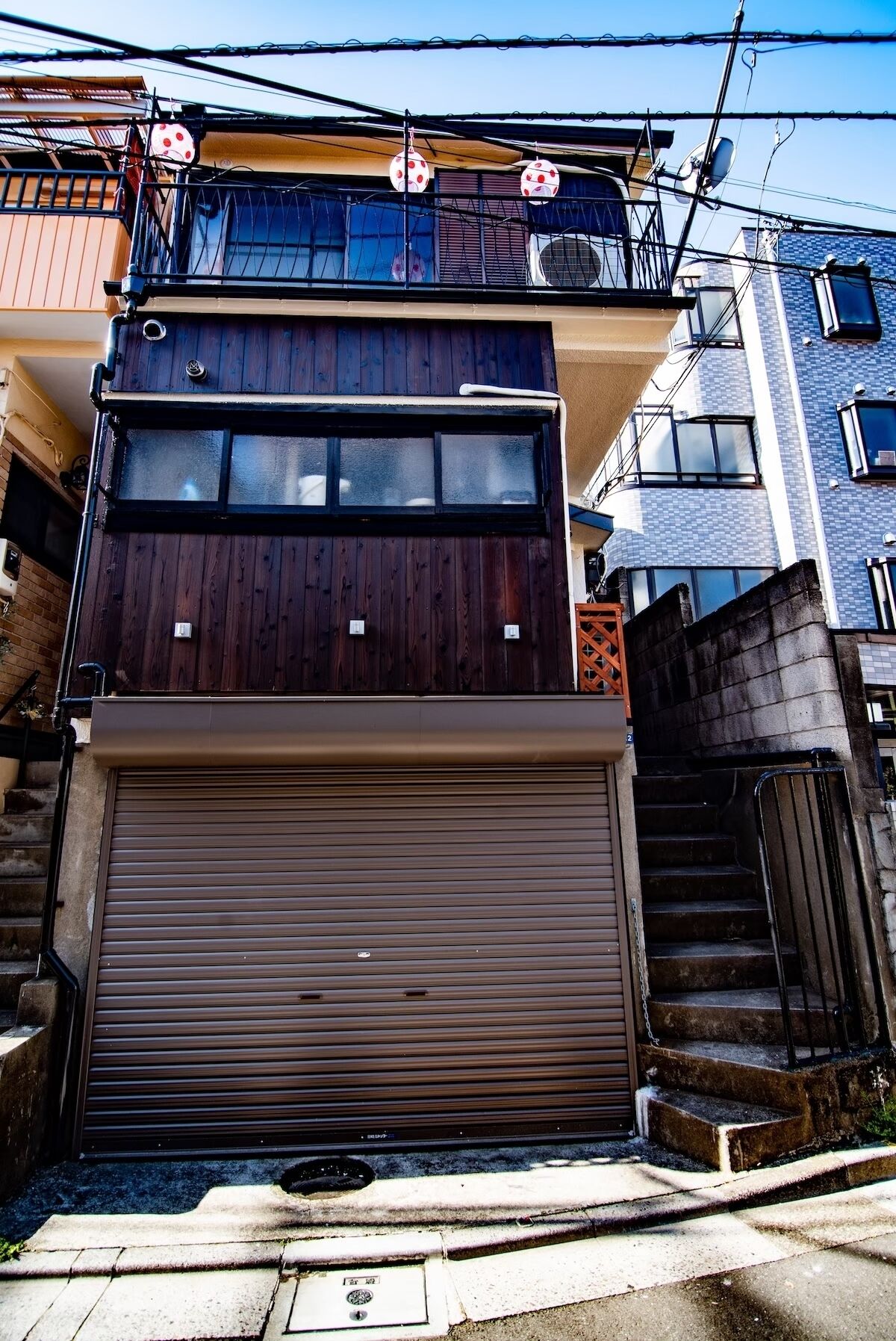 A two-story building with a wooden facade and a brown garage door.