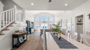A spacious living area with a high ceiling, a staircase, and a dining area with a long table. - Private Heated Pool, walkout on the beach! - Island Star (Dauphin Island)
