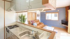 A compact kitchen with a sink, stove, and cabinets. - Kailana Villa (Yomitan)