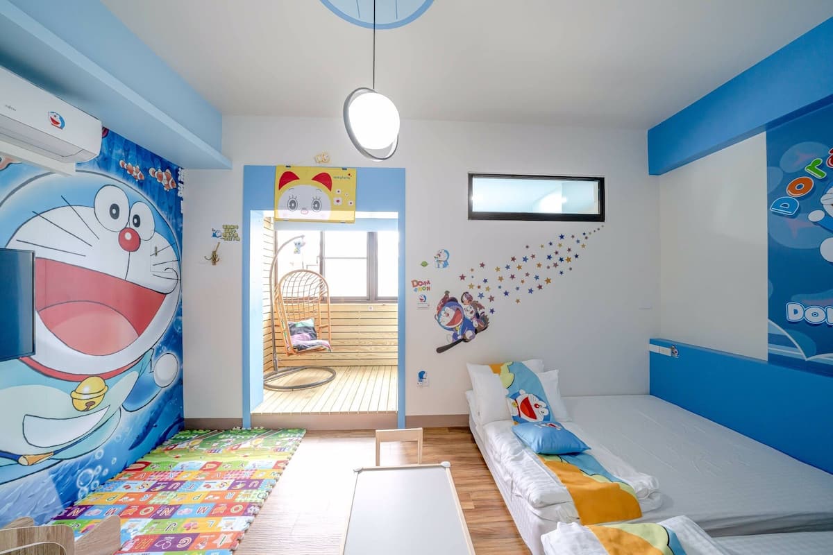 Ein Kinderzimmer mit einer großen Wandmalerei mit einer Comicfigur, einem Etagenbett, einer Spielecke mit einem Hängekorbsessel und einem Fenster mit Blick nach draußen.