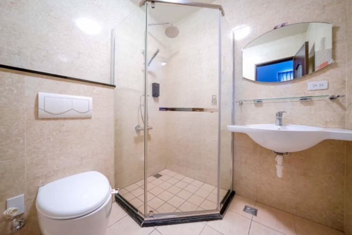 Une salle de bain avec une douche à parois de verre, des toilettes blanches et un lavabo avec un miroir au-dessus.