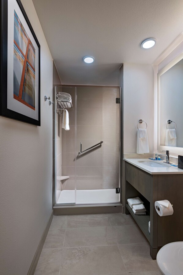A modern bathroom with a glass shower enclosure, a vanity with a mirror, and a toilet.