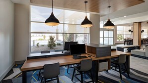 Un espacio de oficina moderno con una larga mesa de madera, varias sillas e iluminación colgante.